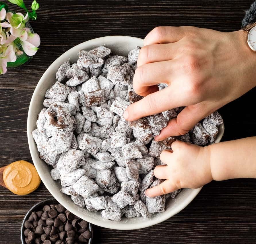 overhead view of two hands reaching into a bowl of puppy chow