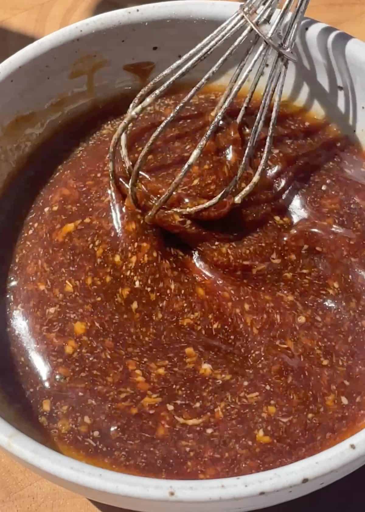 asian chicken lettuce wraps sauce recipe being whisked together in a ceramic bowl with a metal whisk