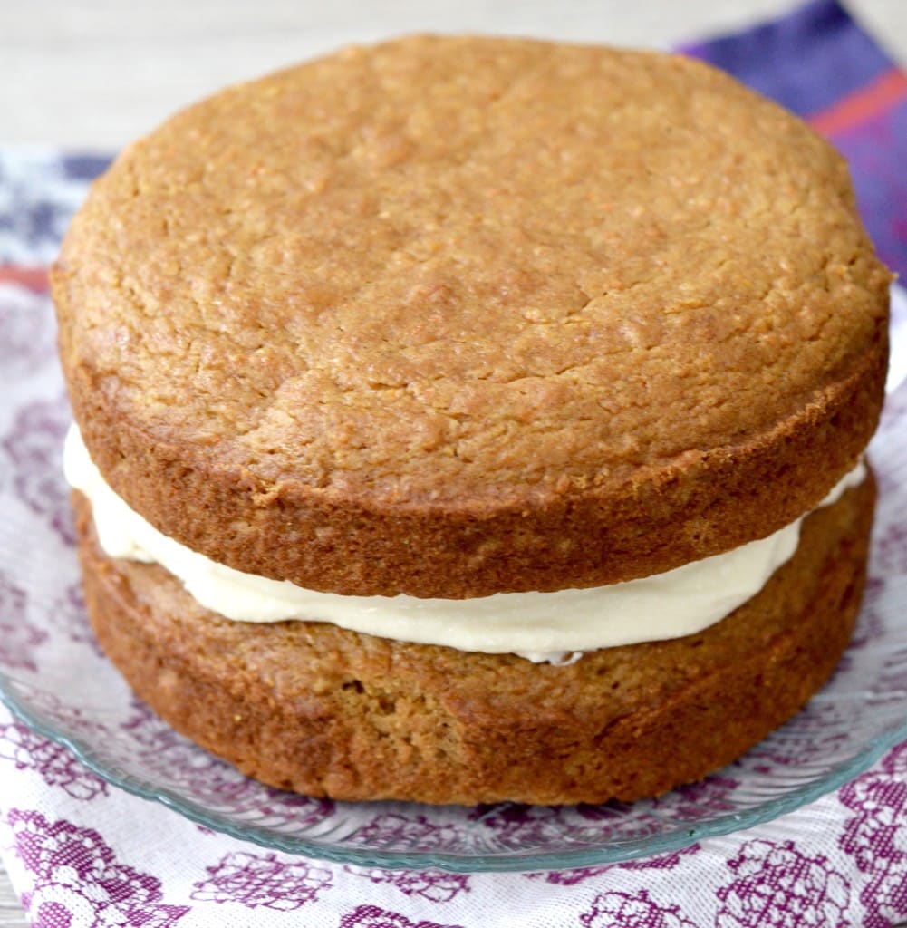 front view of a two-layer Gluten-Free Carrot Cake with frosting in the middle before frosting the outside