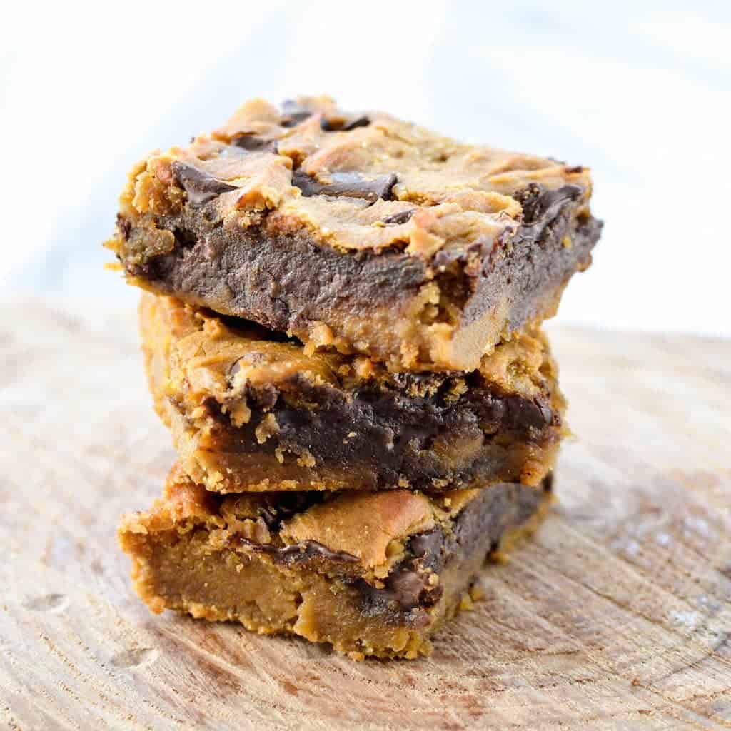 Front view of a stack of three healthy peanut butter blondies made with chickpeas on a wooden surface