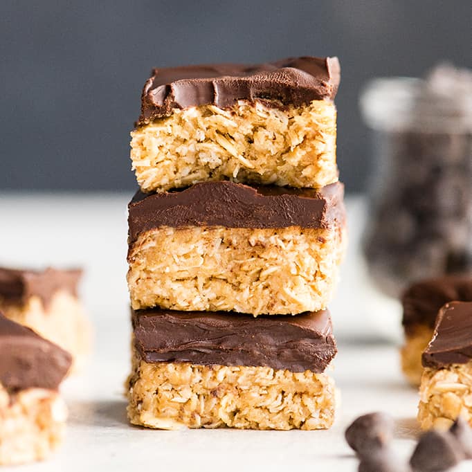 front view of a stack of three No-Bake Oatmeal Bars with Peanut Butter & Coconut, the top one has a bite taken out of it