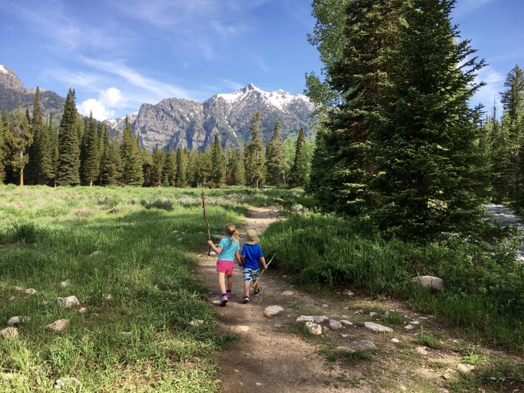 Two kids hiking on a trail in the mountains in The Complete Guide to Hiking with Kids! 