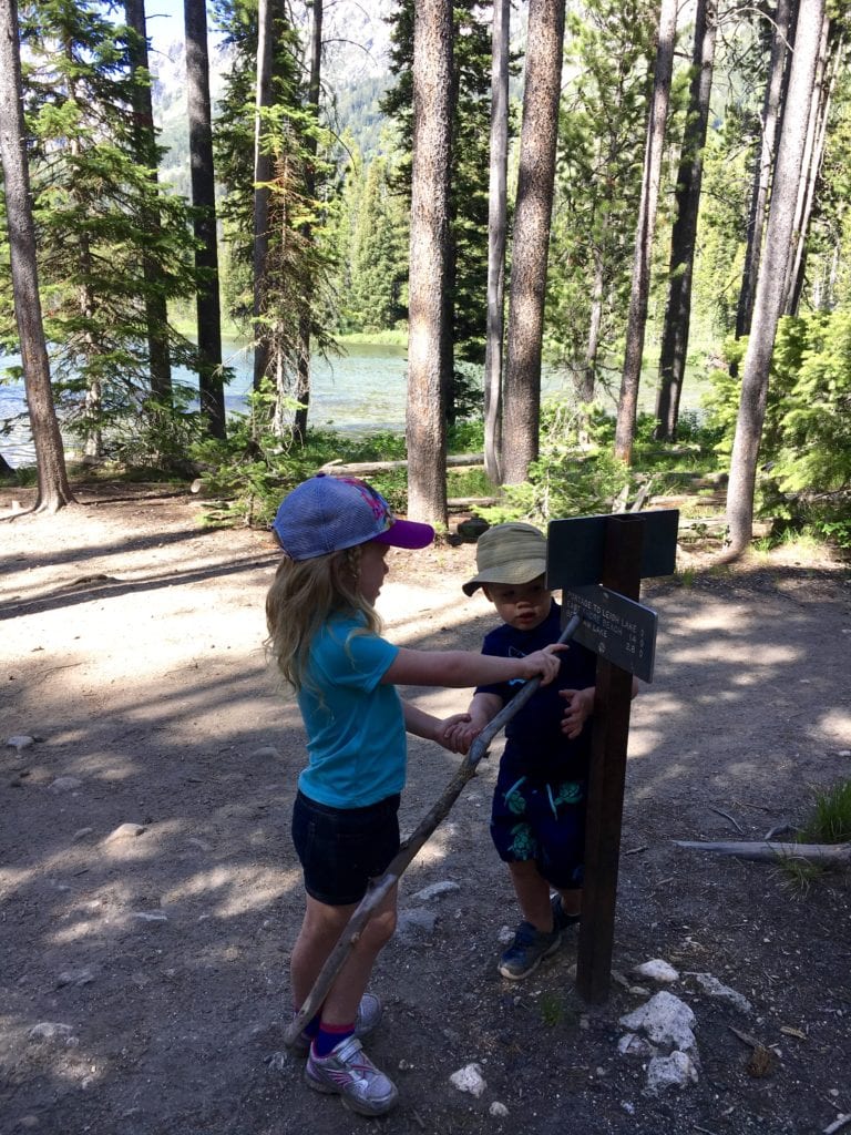 Two kids reading a trail sign in The Complete Guide to Hiking with Kids