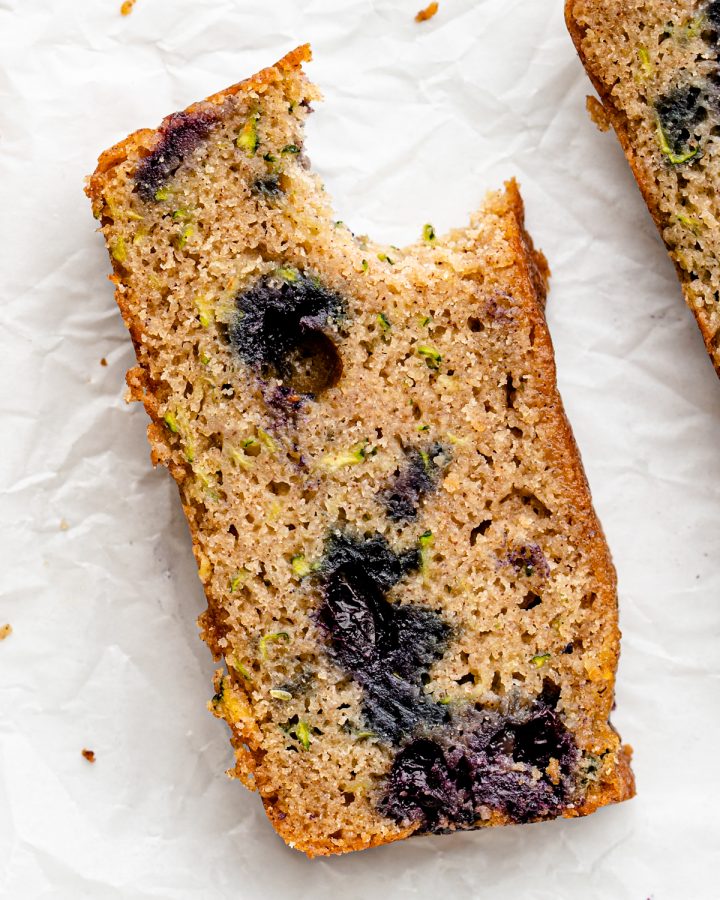 a slice of Blueberry Zucchini Bread with a bite taken out of it