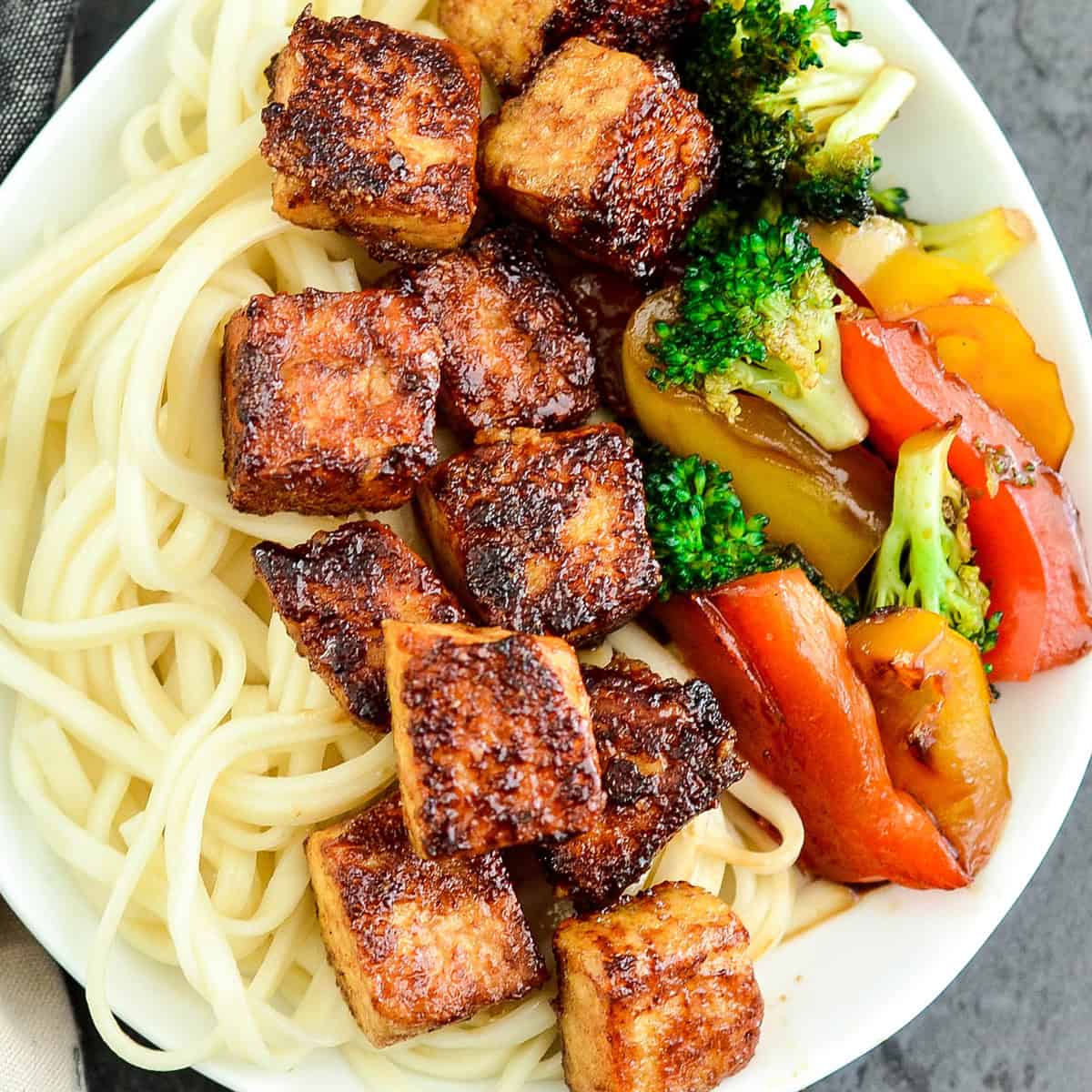 crispy hoisin tofu on a plate with noodles and stir fried vegetables