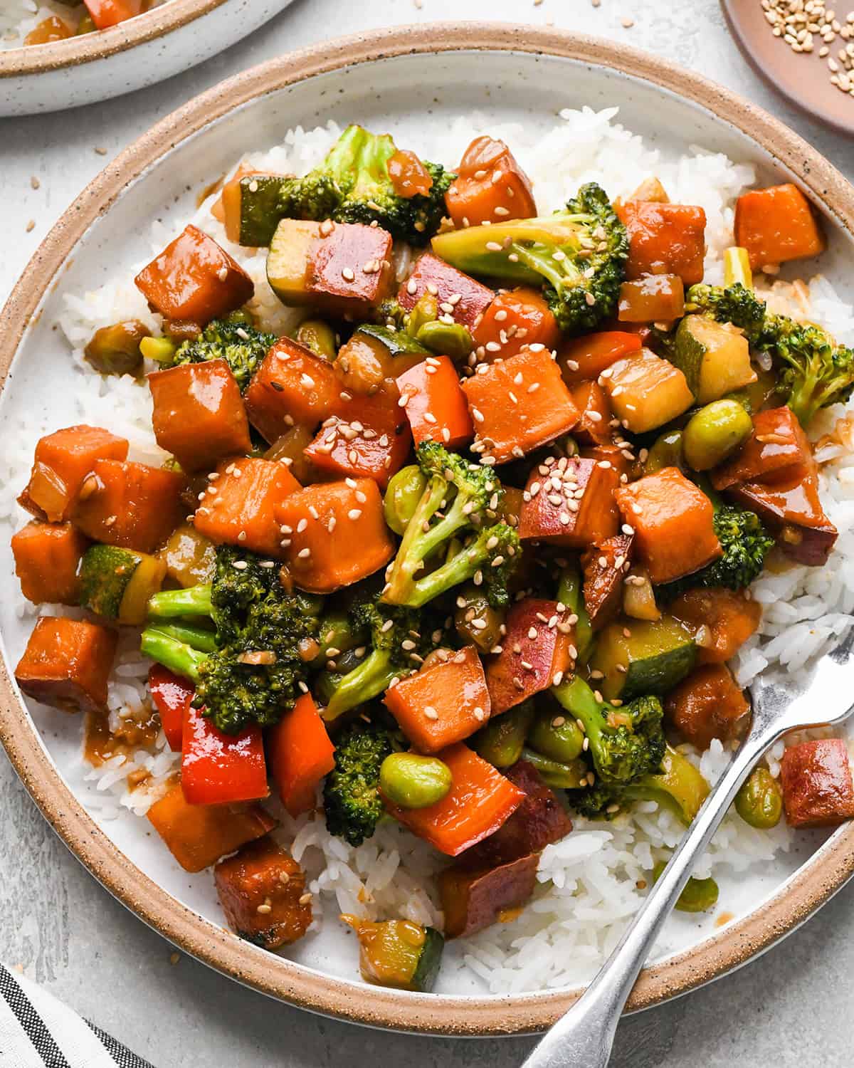 Sweet Potato Stir Fry over rice on a plate with a fork 