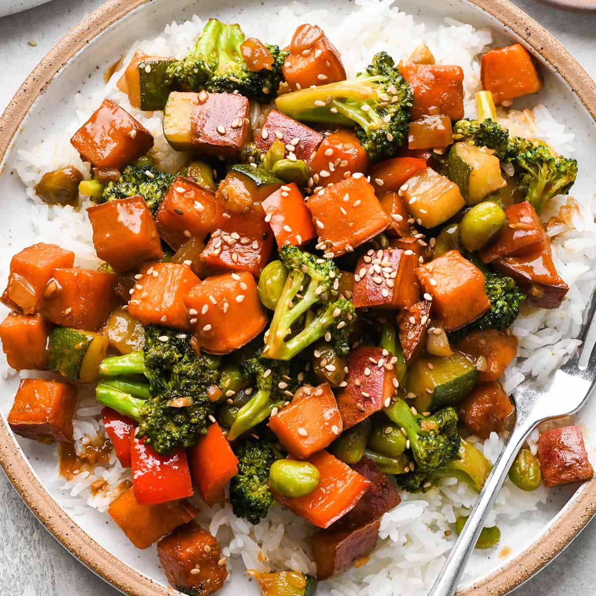 Sweet Potato Stir Fry over rice on a plate with a fork