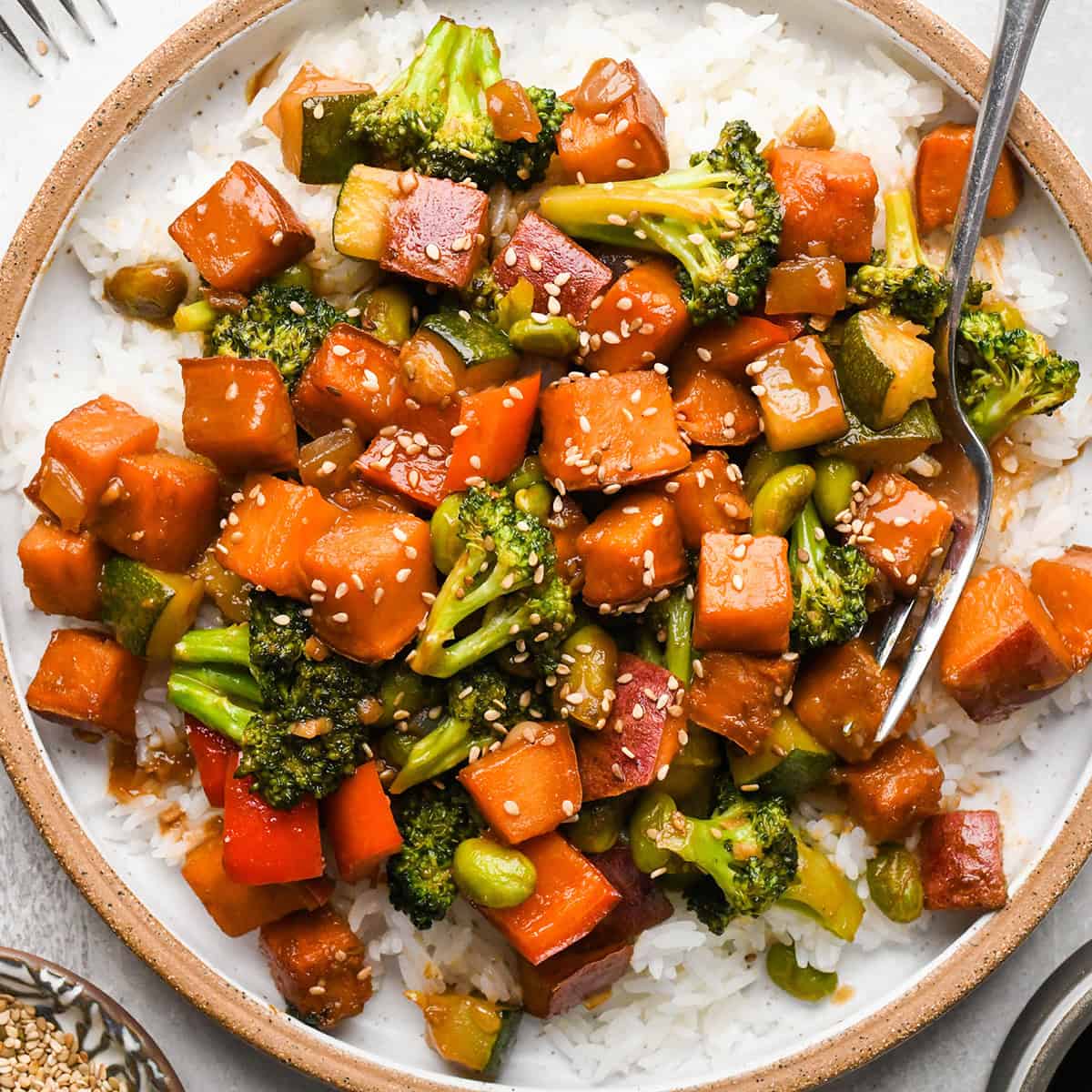 Sweet Potato Stir Fry over rice on a plate with a fork 