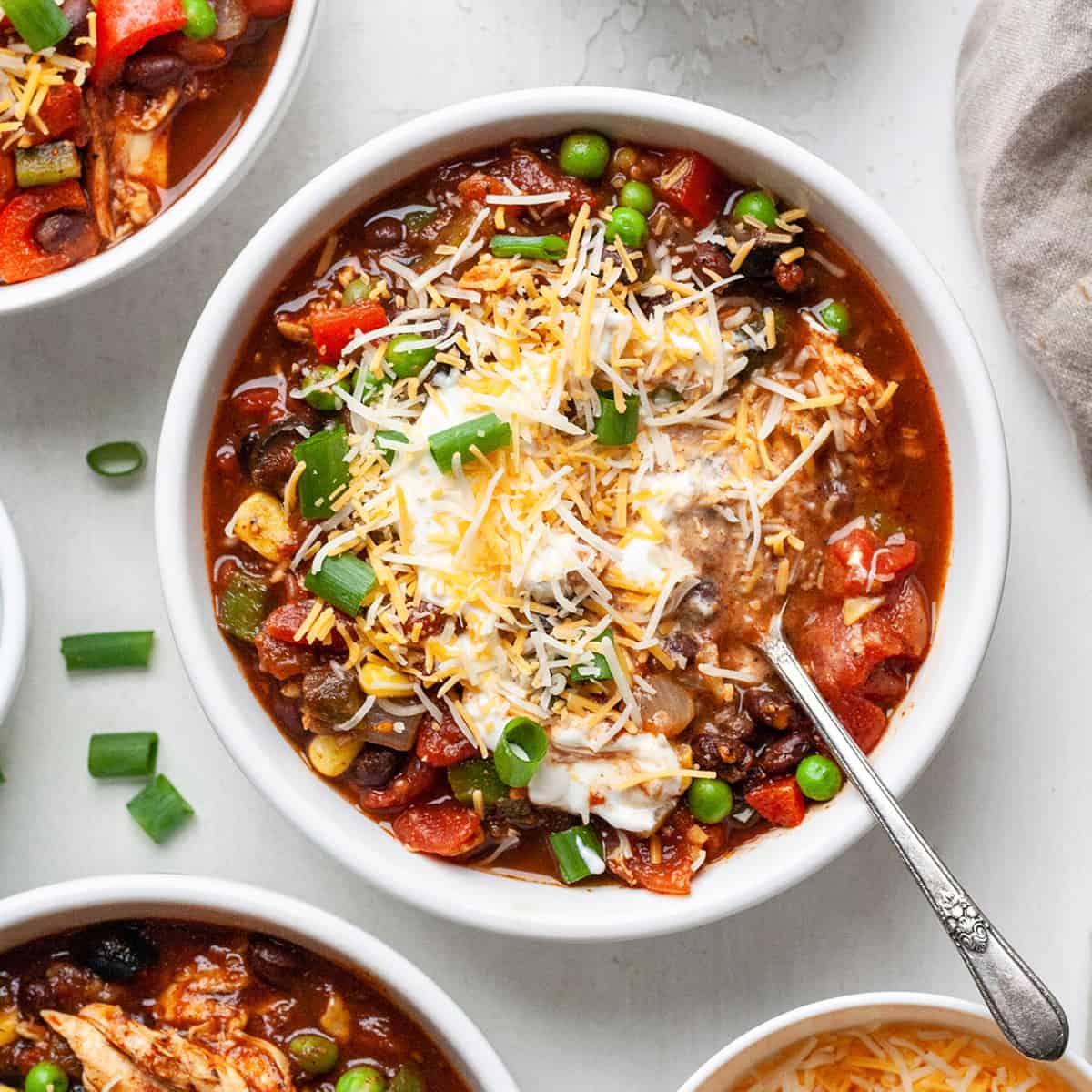 overhead view of a bowl of Crockpot Chicken Chili with cheese, sour cream and green onions 