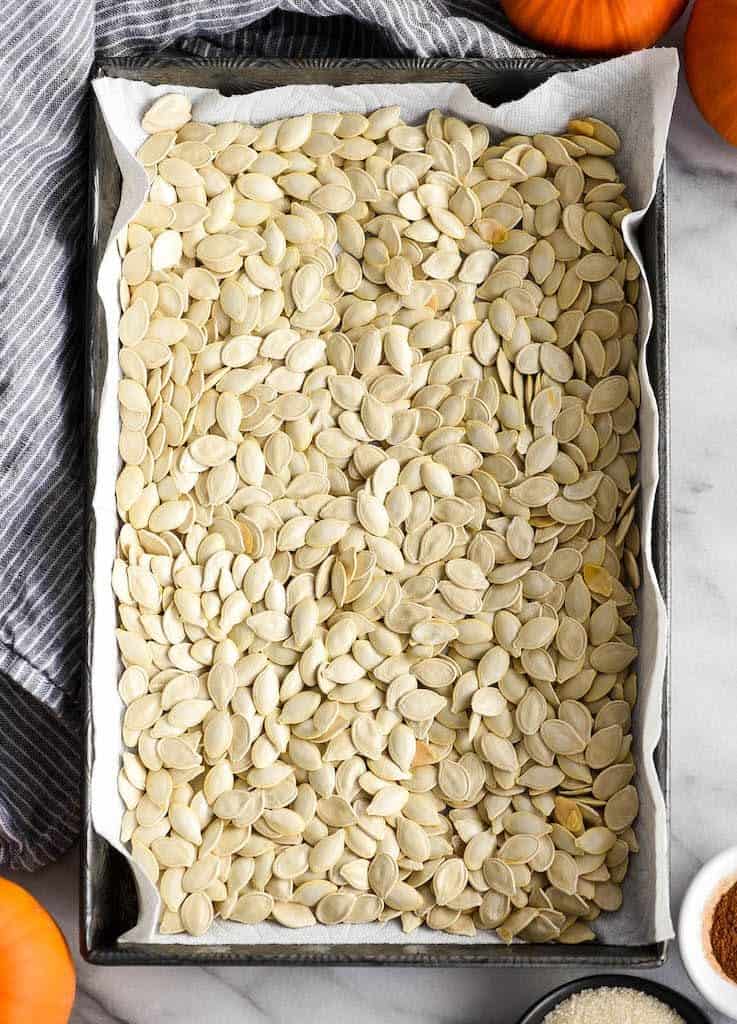Overhead view of Homemade Cinnamon Sugar Pumpkin Seeds in a baking pan after being dried