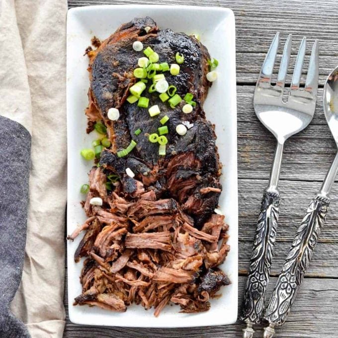 Overhead view of partly shredded Slow Cooker Balsamic Pot Roast sprinkled with green onions