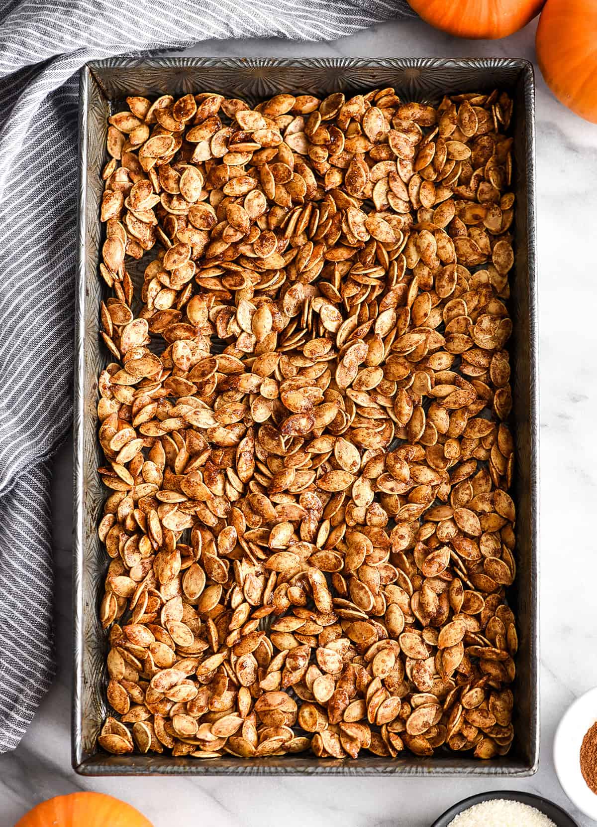 overhead view of cinnamon sugar pumpkin seeds in a baking pan after being roasted