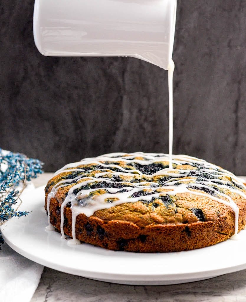Front view of more glaze being drizzled on dairy-free healthy Blueberry Coffee Cake