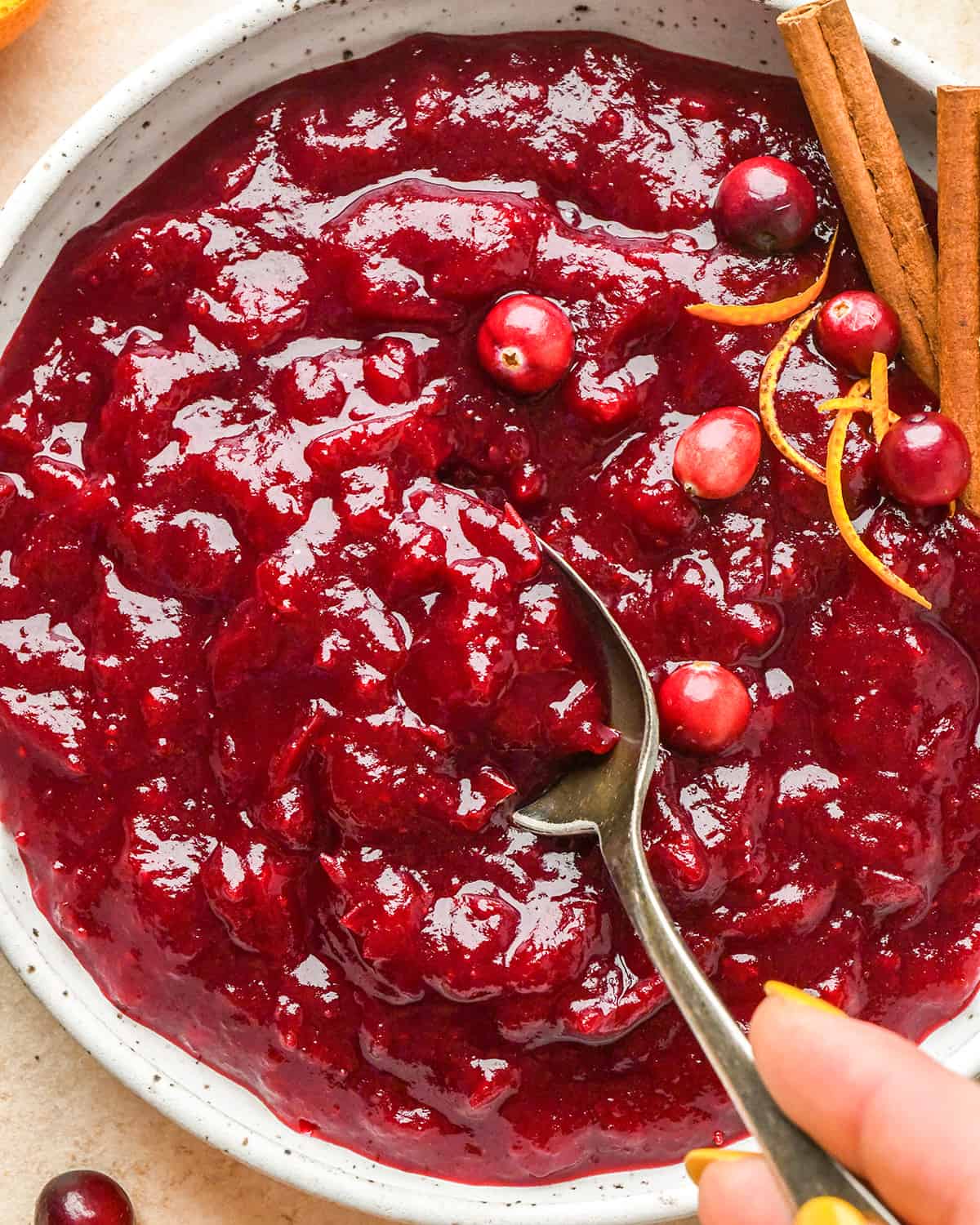 a spoon taking a scoop of cranberry sauce out of a bowl