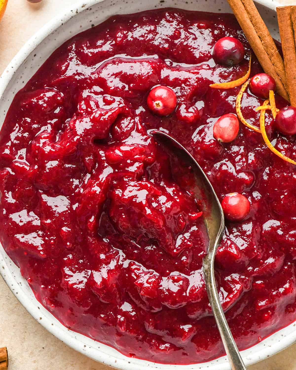 a spoon scooping homemade cranberry sauce in a bowl