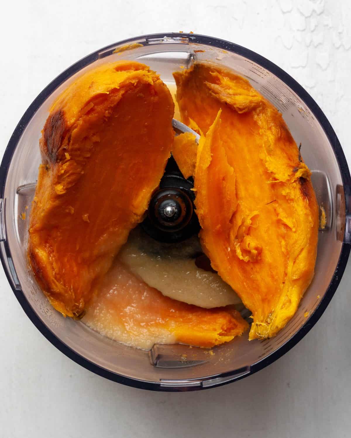 making healthy sweet potato casserole recipe - peeled sweet potato halves in the container of a food processor fitted with the "S" blade before processing.