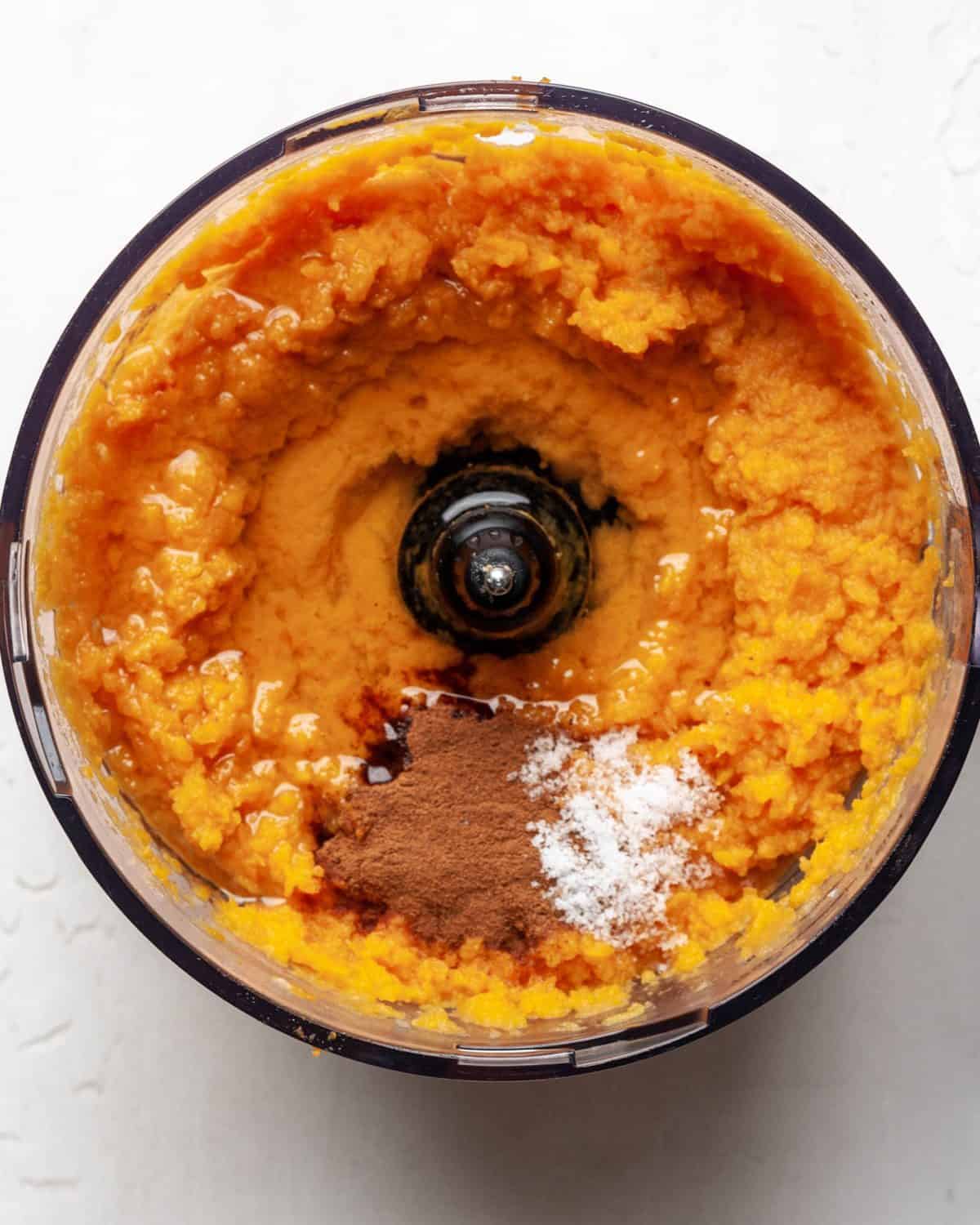 making healthy sweet potato casserole recipe - cinnamon, applesauce, coconut oil, salt and nutmeg added to the sweet potato puree in a food processor fitted with the "S" attachment.