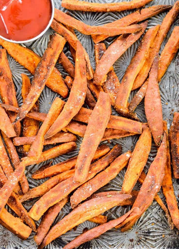 Peanut Butter Crusted Sweet Potato Fries! An easy, healthy side dish recipe made with only 4 ingredients! A light crusting of peanut butter adds protein and makes these sweet potato fries irresistible! Gluten-free, dairy-free, sugar-free and vegan! #sweetpotato #fries #peanutbutter #vegan #glutenfree #dairyfree Overhead view of Peanut Butter Crusted Sweet Potato Fries on a baking sheet