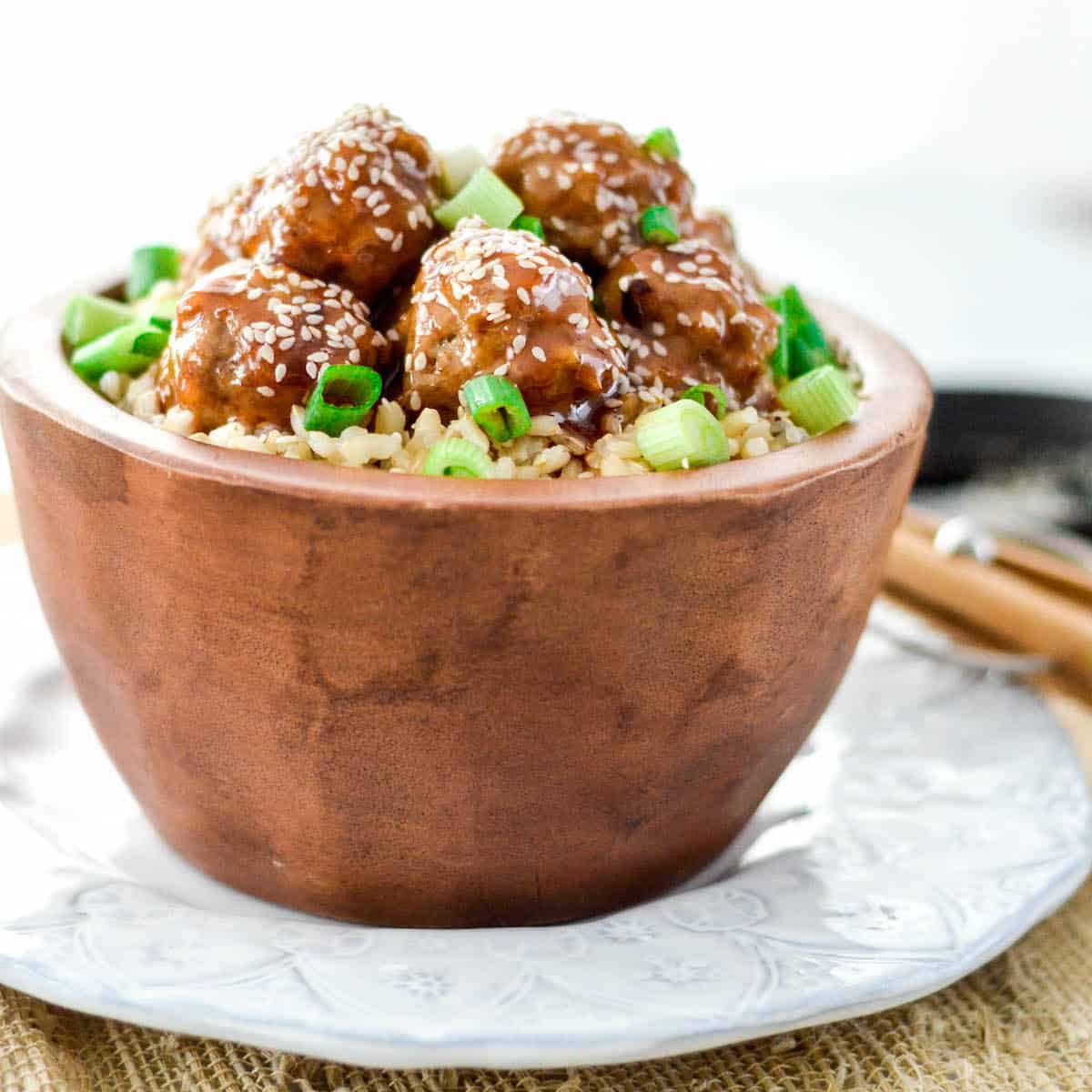 Front view of healthy Paleo Sweet and Sour Meatballs in a bowl with brown rice