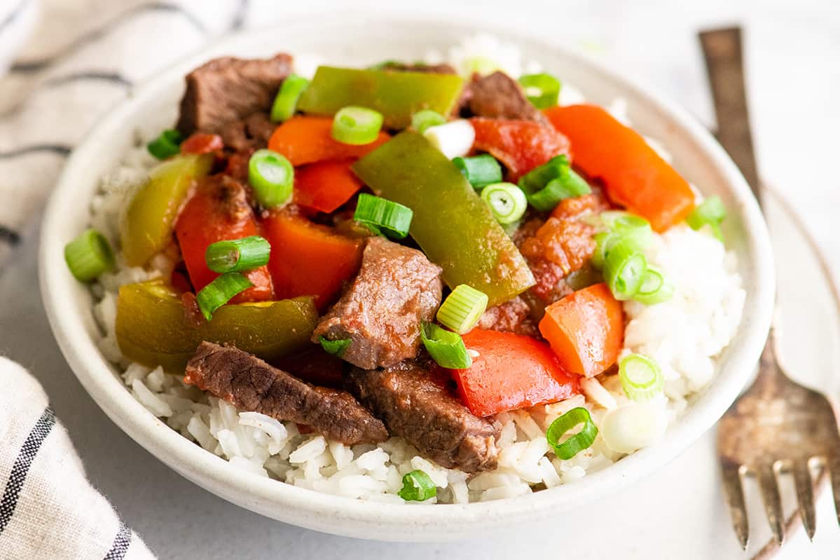 overhead view of slow cooker pepper steak in a bowl over rice