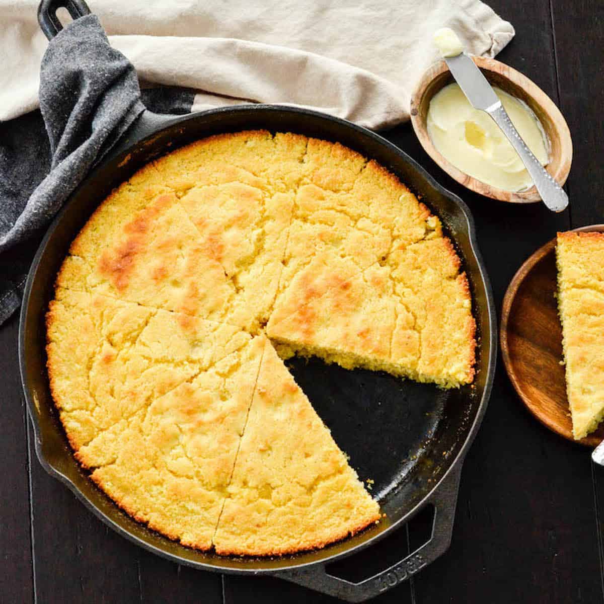 Overhead view of Healthy Skillet Cornbread cut into 8 pieces in a cast iron skillet with one piece removed