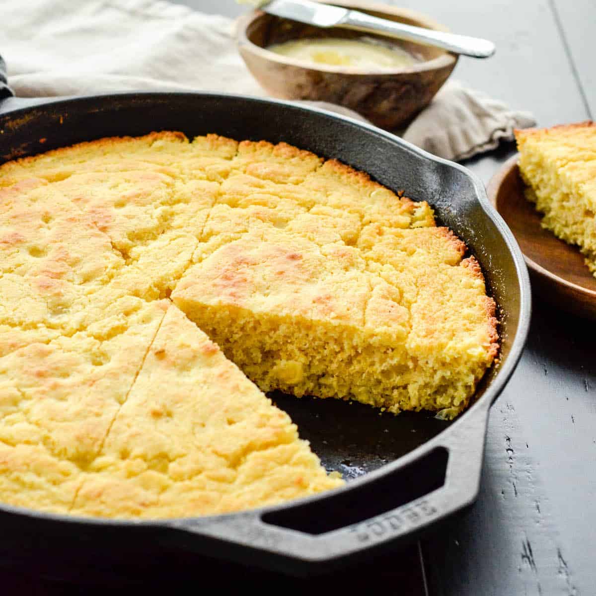 Side view Healthy Skillet Cornbread recipe in a cast iron skillet cut into pieces with one removed