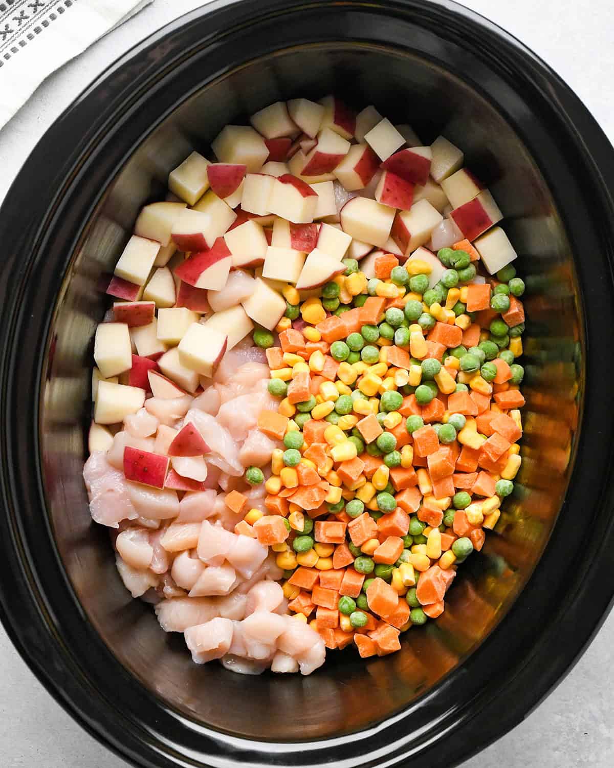 making Chicken Pot Pie Soup - potatoes, chicken and vegetables in a crock pot