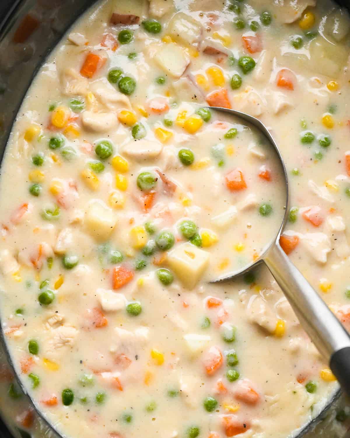 a ladle taking a scoop of chicken pot pie soup in slow cooker