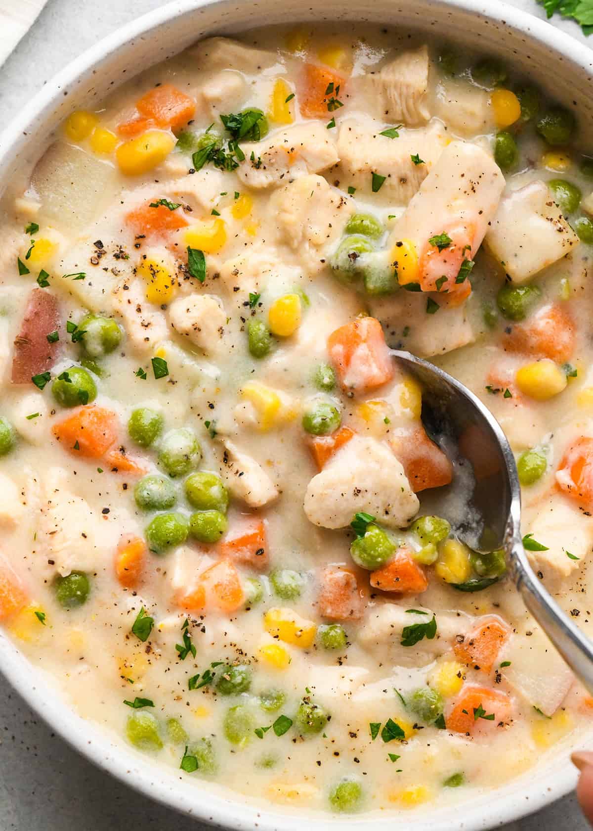 a spoon taking a scoop of chicken pot pie soup in a bowl