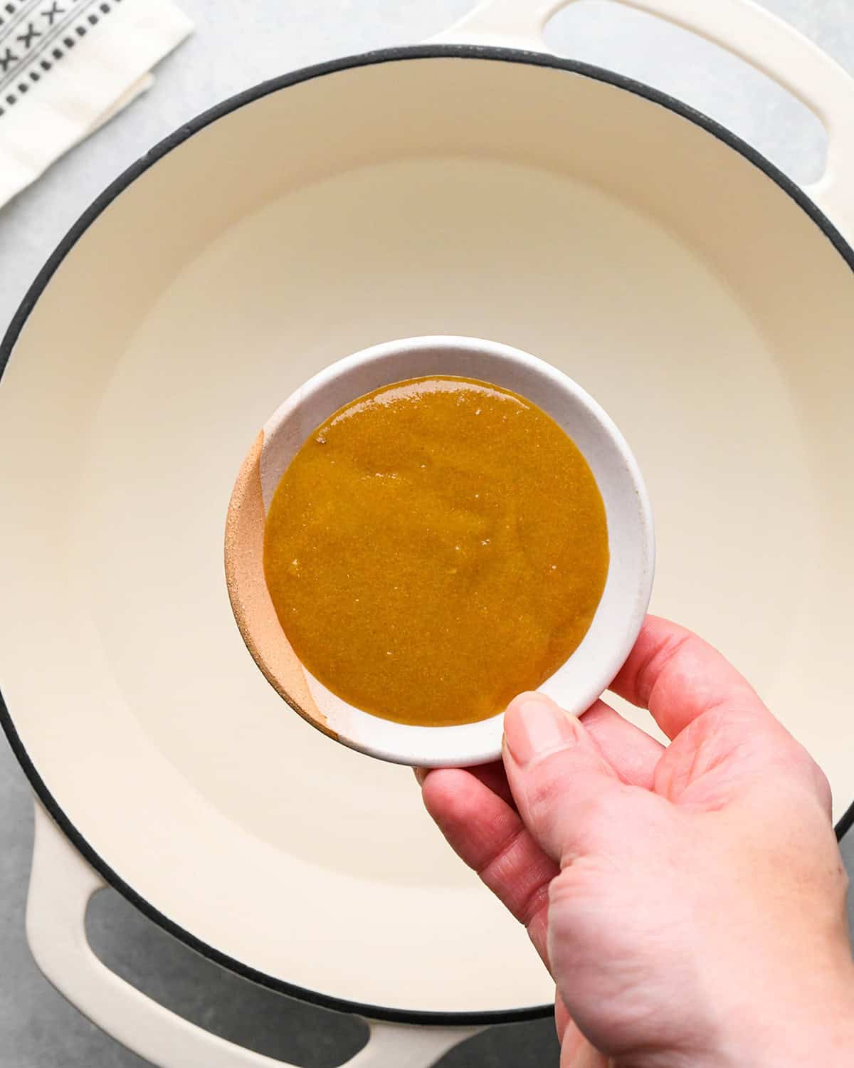 making Chicken Pot Pie Soup - a bowl of chicken bouillon being held above a pot of boiling water