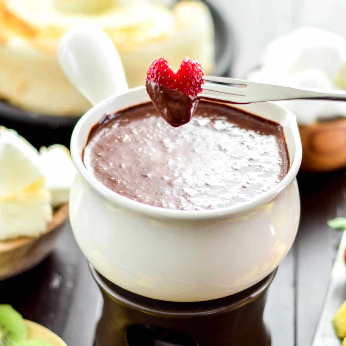 Front view of a heart-shaped strawberry that has been dipped into Vegan Chocolate Fondue