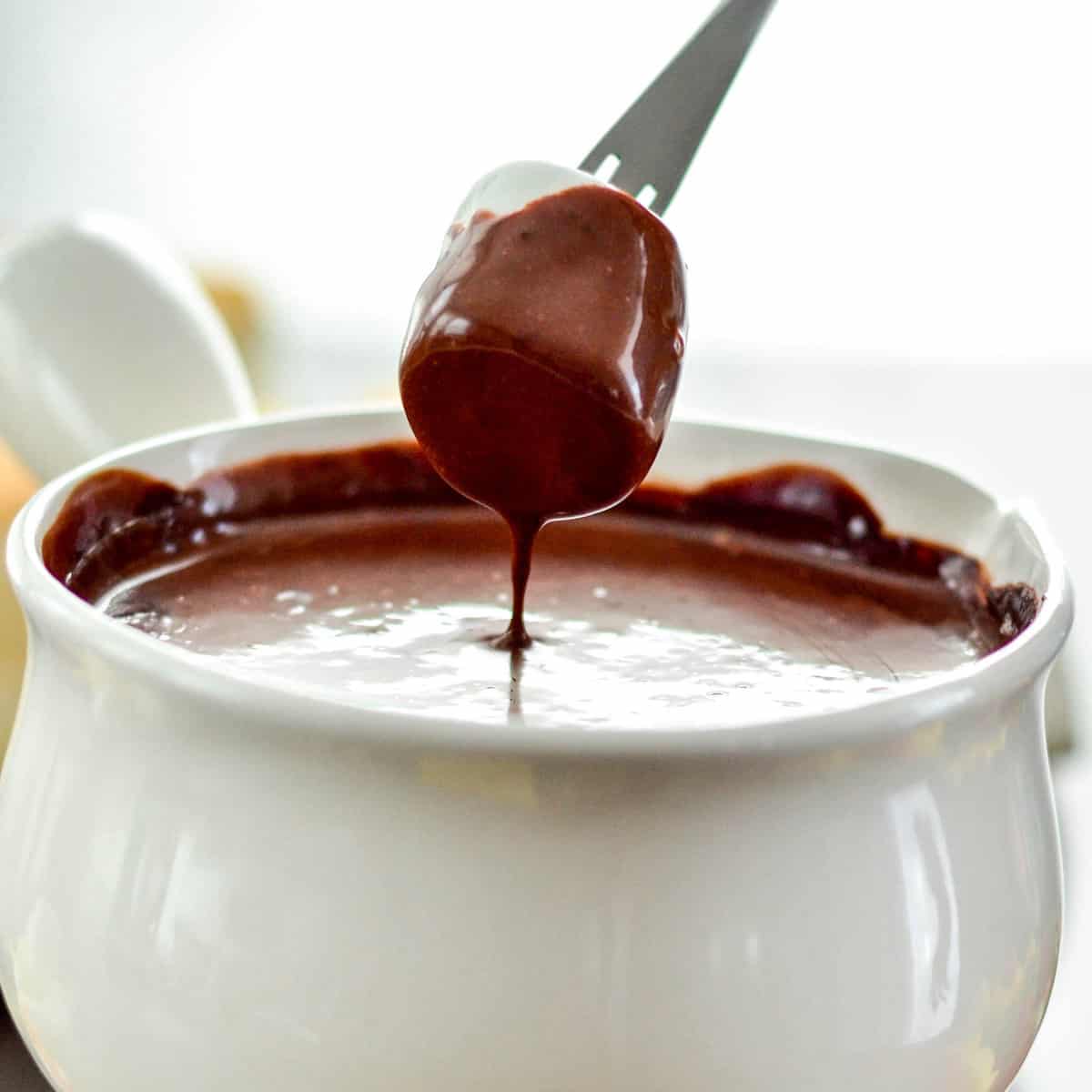 Front view of a marshmallow being dipped into Vegan Chocolate Fondue