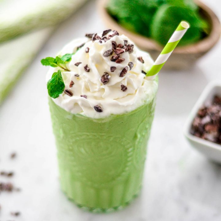 side view of a healthy shamrock shake with whipped cream, fresh mint and chocolate shavings