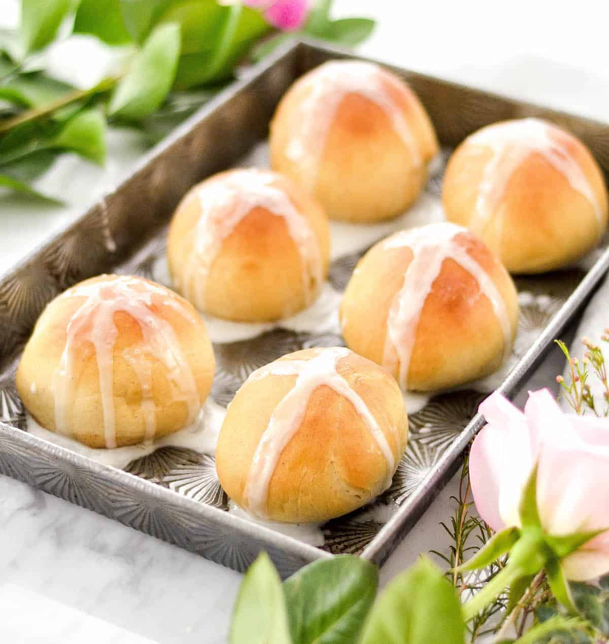 Side view of baked homemade resurrection rolls on the pan with white glaze 