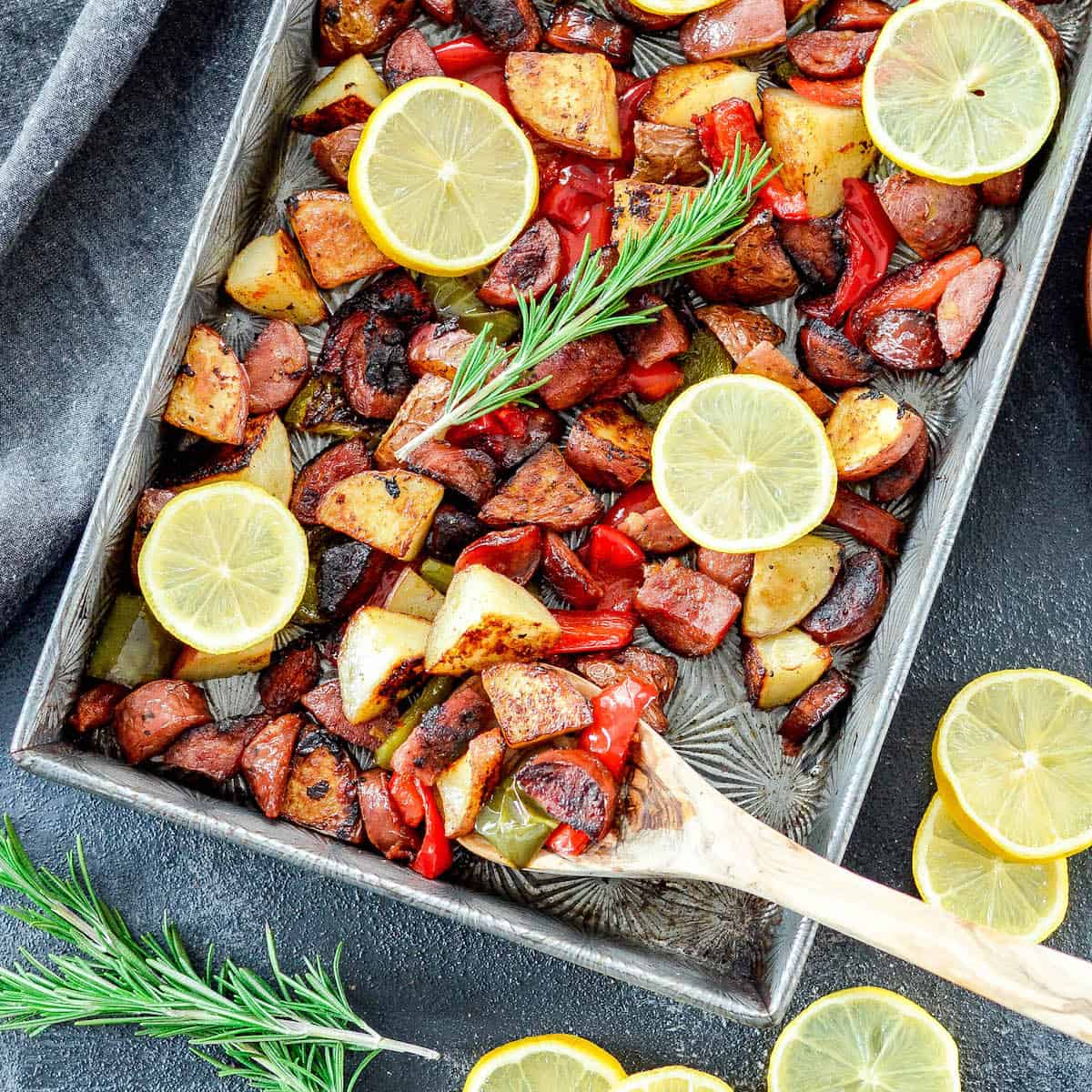 a spoon scooping Sheet Pan Roasted Sausage & Potatoes with Peppers