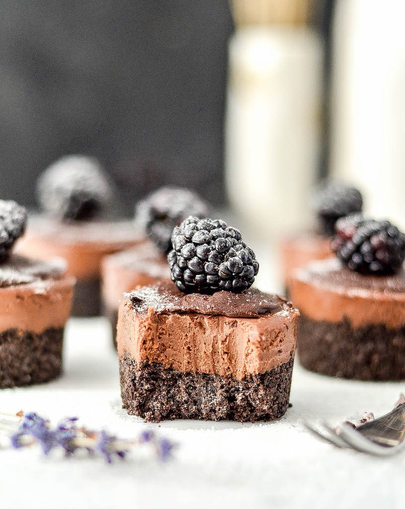 Front view of one Mini No-Bake Vegan Chocolate Cheesecakes with a bite taken out of it with 5 others in the background