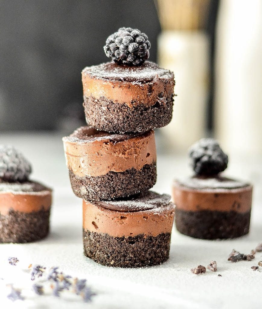 Front view of a stack of three Mini No-Bake Vegan Chocolate Cheesecakes with a blackberry on top
