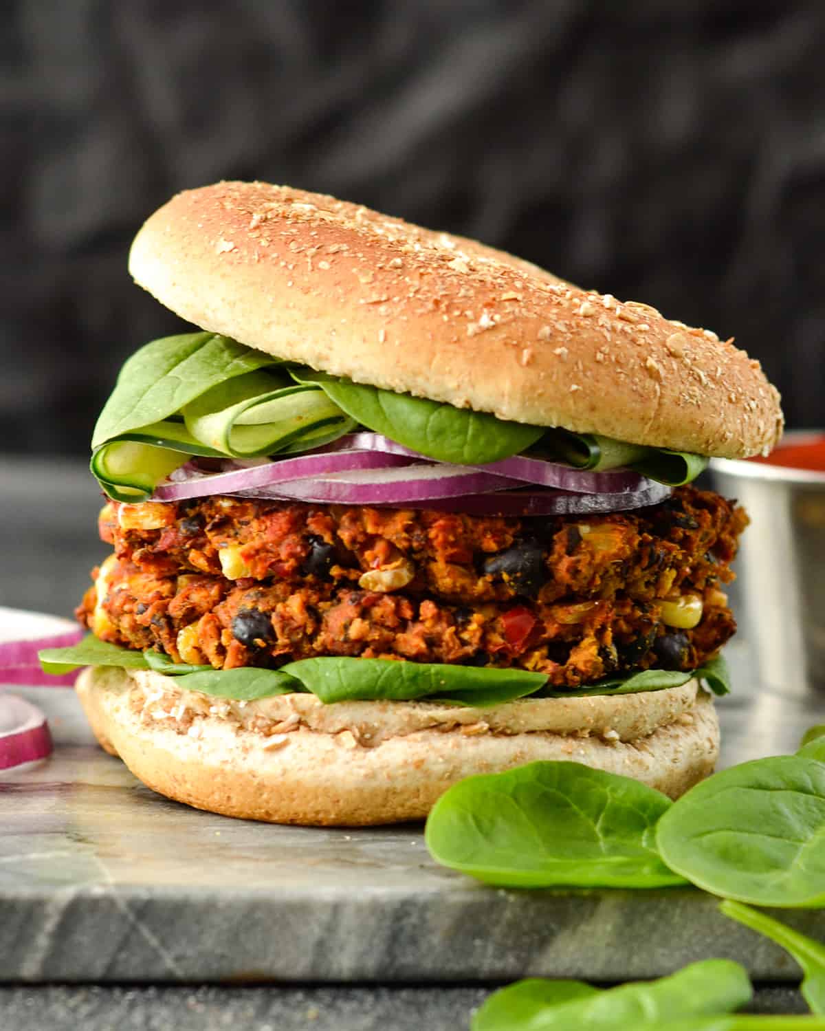 Front view of a Baked Sweet Potato Black Bean Veggie Burger with two patties on a bun with lettuce and red onion