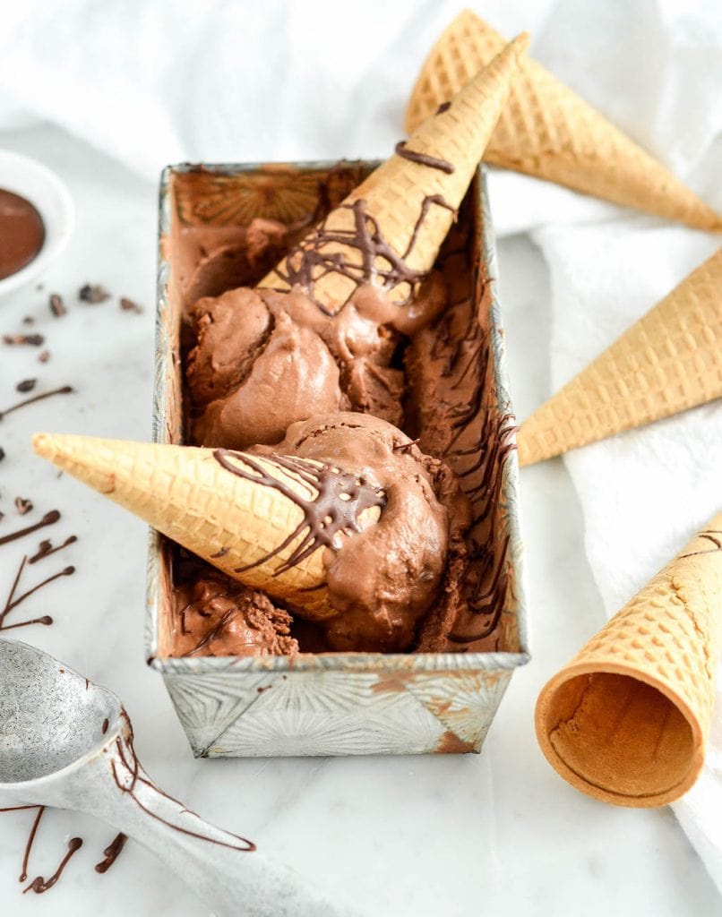side view of a rectangular metal container filled with paleo chocolate ice cream with two cones in it 