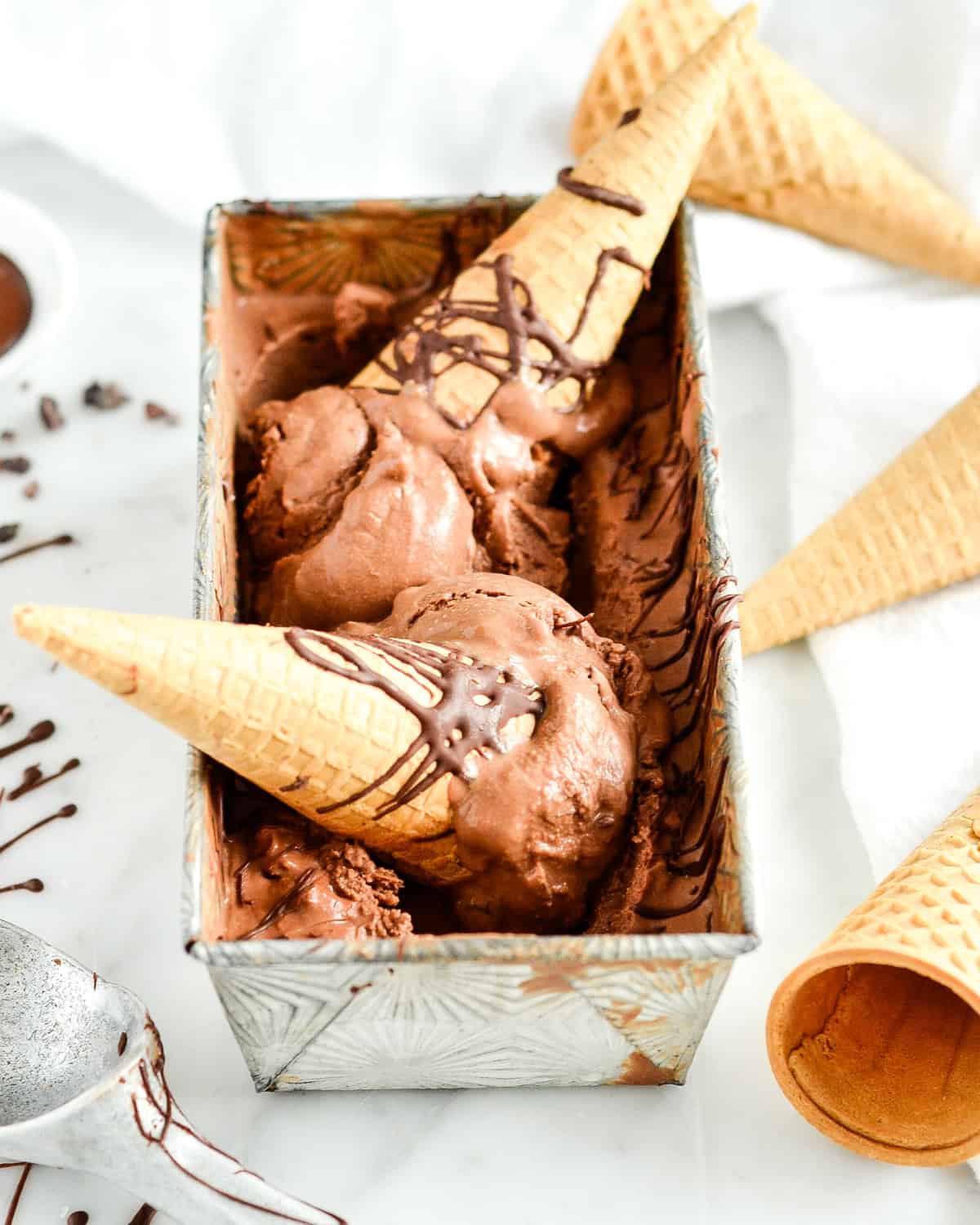 Paleo Chocolate Ice Cream in a container with ice cream cones