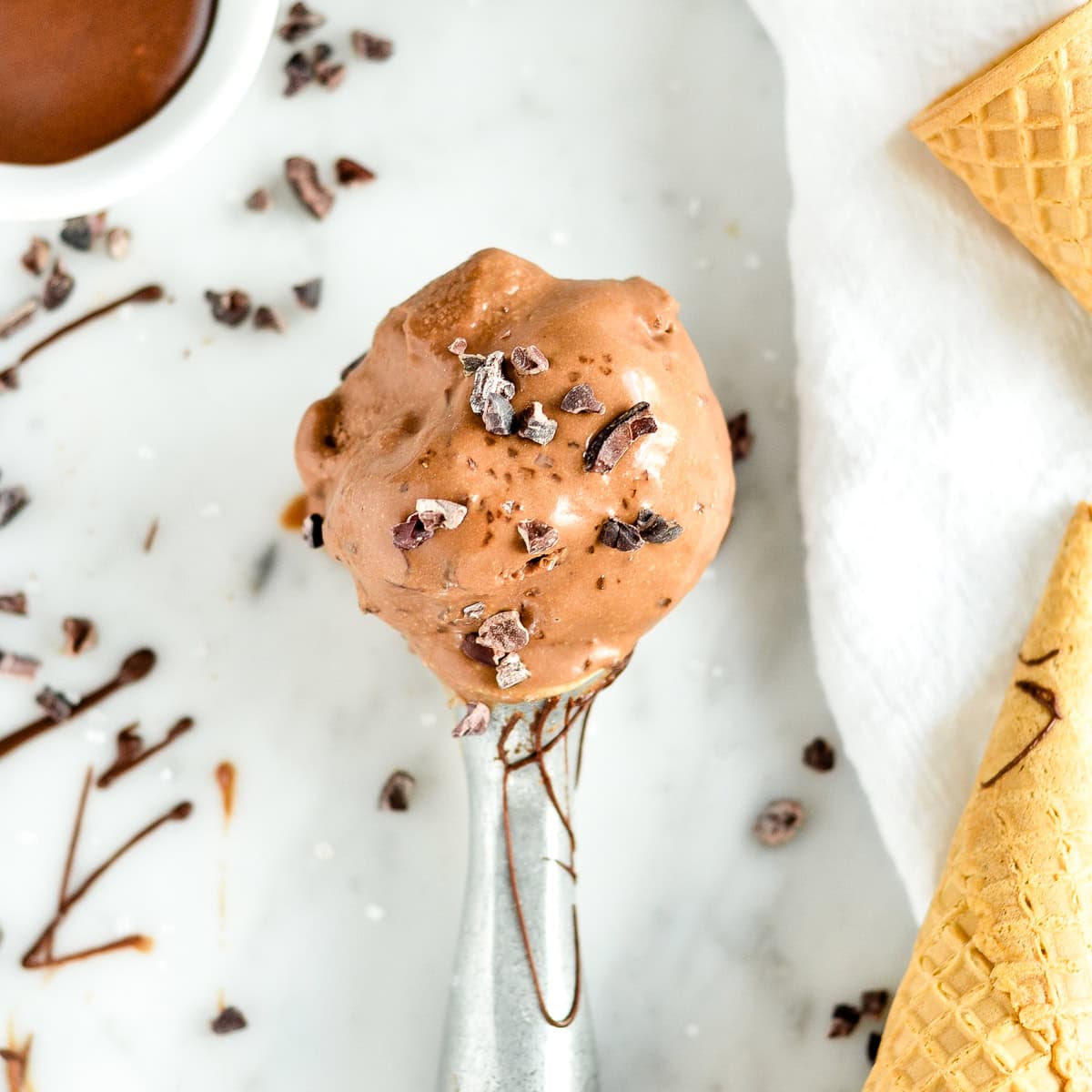 an ice cream scoop with Paleo Chocolate Ice Cream and cocoa nibs