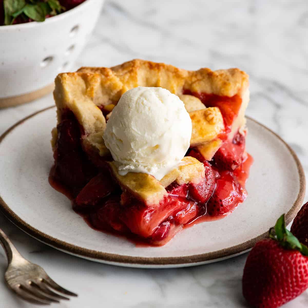 slice of strawberry pie on a plate with a scoop of ice cream on top