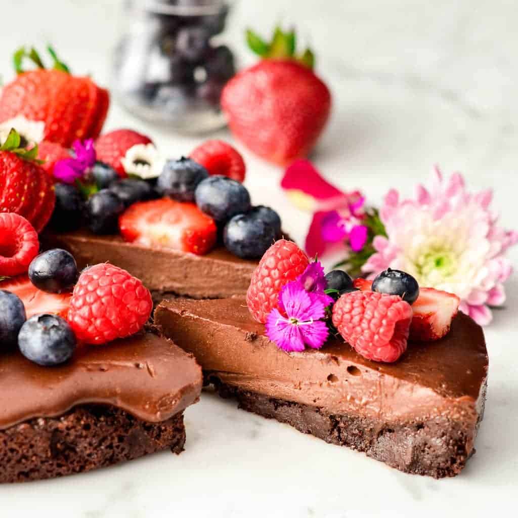 front view of a slice of Paleo Chocolate Fruit Pizza with a Brownie Cookie Crust being pulled away from the entire fruit pizza