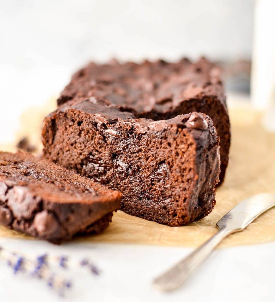 Front and side view of a two pieces of Double Chocolate Paleo Zucchini Banana Bread cut out of the loaf, one laying down and one standing up with gooey chocolate chips