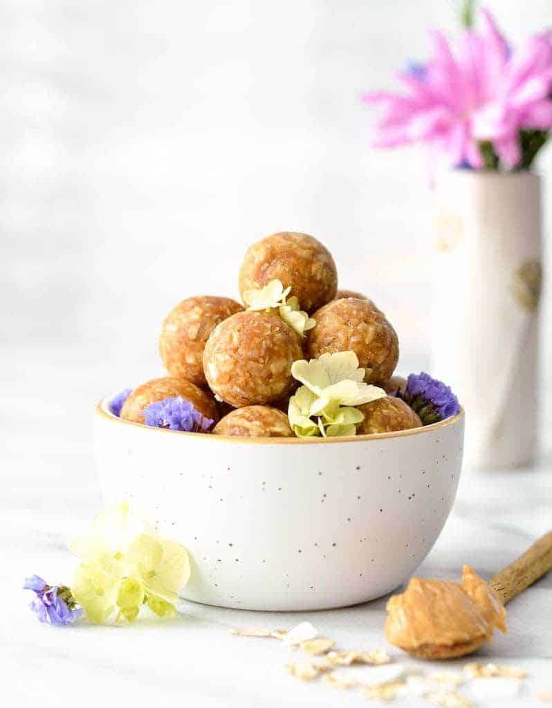 Front view of Peanut Butter Oatmeal Balls in a bowl with flowers in the background