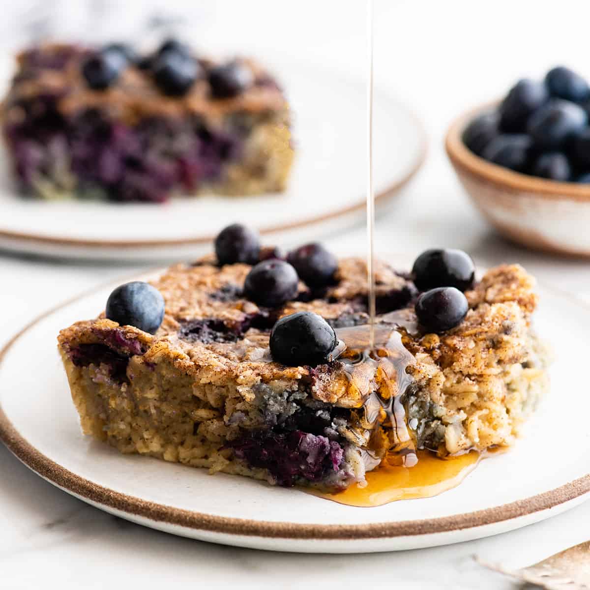 front view of syrup being poured onto a piece of Blueberry Baked Oatmeal on a plate