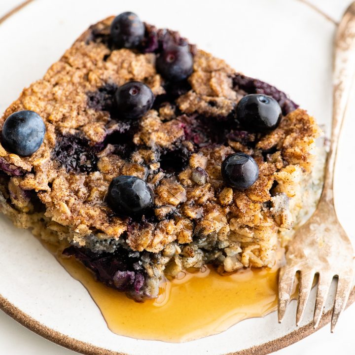overhead photo of a slice of blueberry baked oatmeal on a plate with syrup