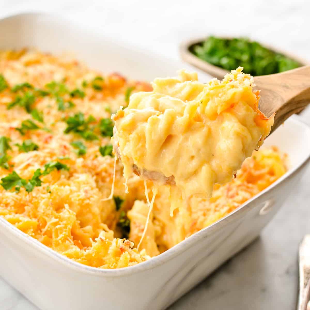 front view of a spoon taking a scoop of Greek Yogurt Mac & Cheese from a baking dish