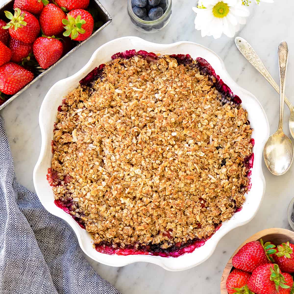 Overhead view of Healthy Berry Crisp Recipe in a pie dish surrounded by berries