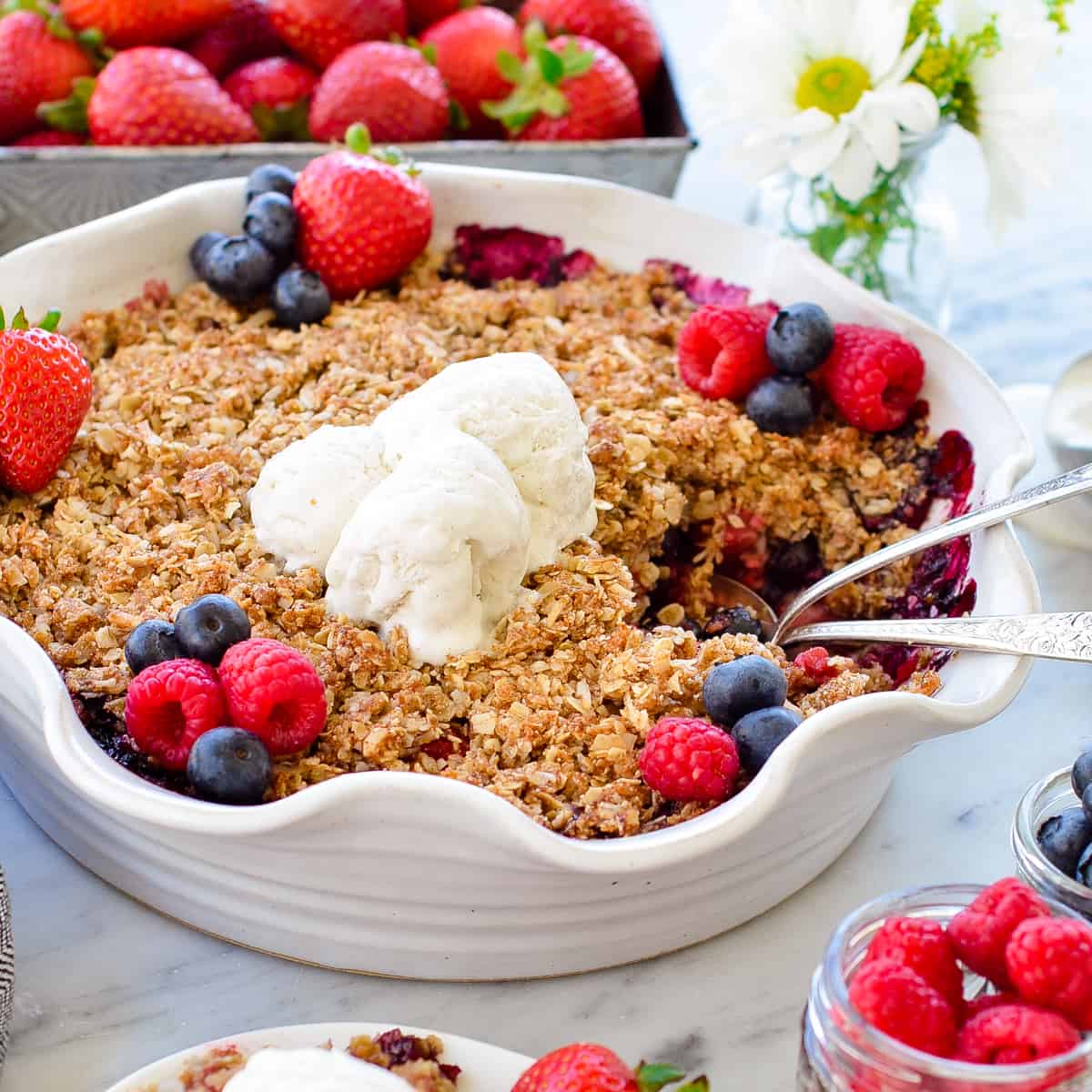 Side view of a pie dish of Healthy Berry Crisp with two spoons in it